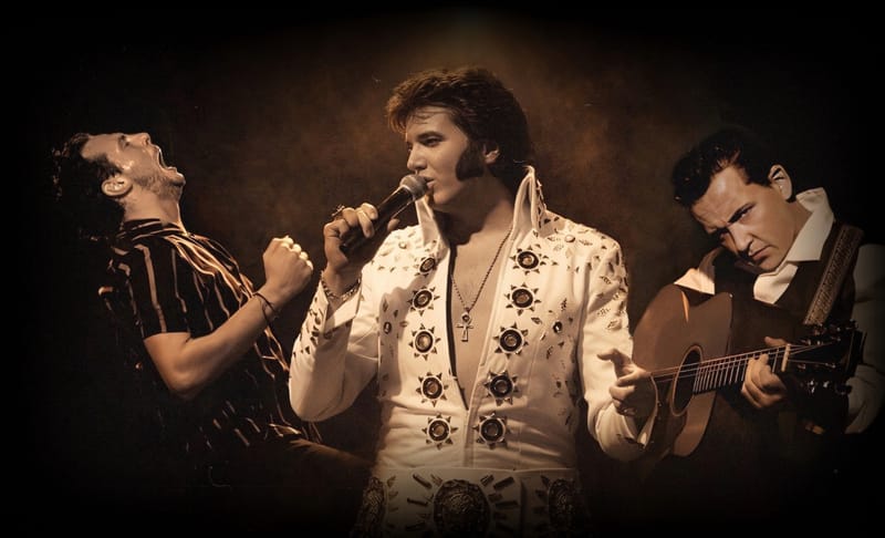 Tribute artists in amber stage light: Jerry Lee Lewis mid-shout, Elvis Presley in a white jumpsuit at the microphone, and Johnny Cash with an acoustic guitar.